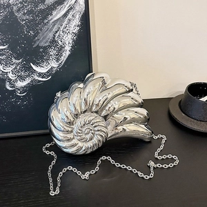 Détail macro du sac de soirée en forme de nautile argenté avec une finition miroir
