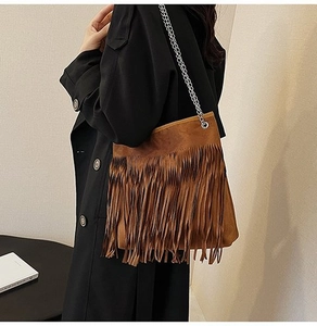 Detail of a brown suede shoulder bag featuring long fringe in a bohemian retro style