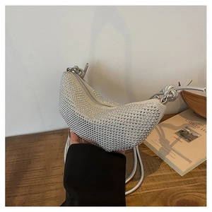 Detalle de bolso medialuna plateado con pedrería brillante y correa con nudo elegante