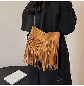 Close-up of a vintage ginger fringe shoulder bag with silver chain strap on a model