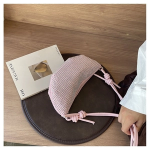 Bolso rosa de media luna con pedrería brillante y detalle de correa anudada a la moda