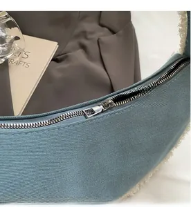 Détail d'une fermeture éclair argentée sur un sac croissant en denim bleu et fausse fourrure
