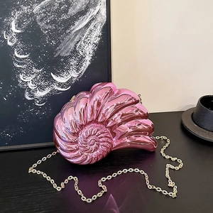 Détail de la pochette coquillage rose métallisé avec une bandoulière en chaîne dorée