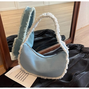 Vue détaillée du sac hobo croissant en denim bleu clair avec garnitures à franges blanches