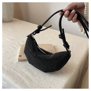Detalle del bolso de media luna negro con pedrería y asa de cuero con nudos