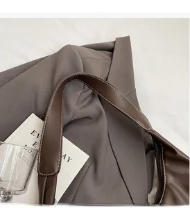 Detailed close-up of dark brown leather handbag with contrast stitching and sturdy handle