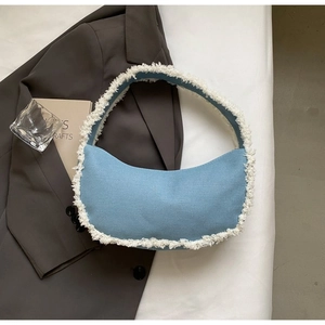 Détail du sac croissant en denim avec bordure en simili mouton blanc et surpiqûres