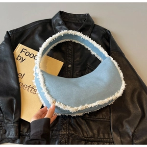 Détail du sac croissant en denim bleu clair avec franges blanches et fermeture éclair