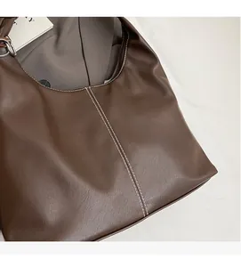 Detailed close-up of brown PU leather tote bag with stylish white contrast stitching