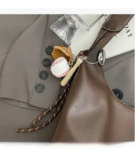 Detail of baseball charm with bat and glove accessory on a brown shoulder bag
