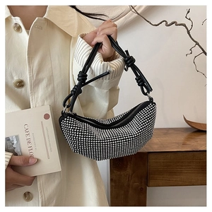 Detalle de bolso medialuna negro con diamantes de imitación y correa de cuero con nudos