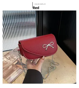 Dettaglio borsa rossa in pelle martellata con chiusura a fiocco argento e catena