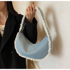 Détail du sac croissant en denim bleu clair avec finitions en peau lainée blanche