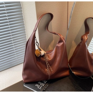 Close-up of brown leather bag with white stitching and baseball themed keychain charm