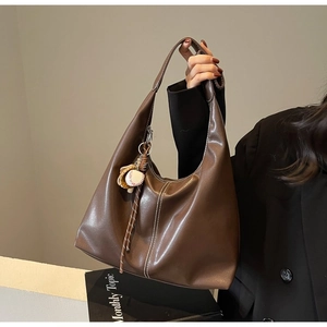 Detail of dark brown tote bag with white contrast stitching and baseball bag charm