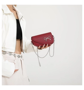 Dettaglio borsa in pelle bordeaux con fiocco in metallo argento e tracolla a catena