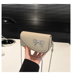 Dettaglio mini borsa beige testurizzata con fibbia a fiocco argento e catena a sfere