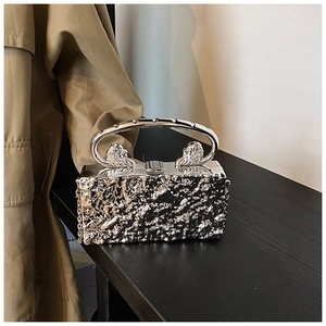 Detail of silver acrylic clutch with lava texture and lion head metal handle accents