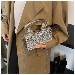 Detail of silver metallic clutch bag with stone texture and lion head metal handle