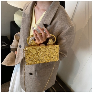 Detail of gold acrylic clutch with lava texture, lion head relief and ring handle