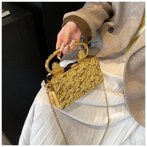 Detail view of gold evening clutch with hammered texture and lion head ring handle