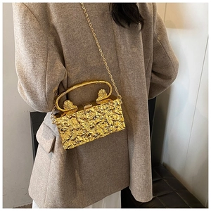 Detailed view of golden acrylic clutch bag with lava texture and lion head handle detail