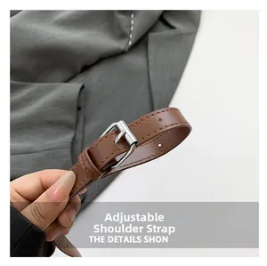 Detail shot of brown leather adjustable shoulder strap with silver buckle and fine stitching