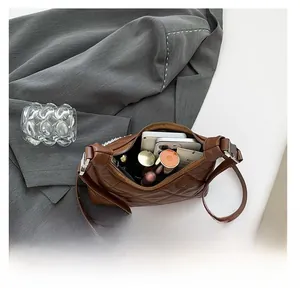 Detailed interior view of brown quilted crescent bag showing phone and lipstick storage