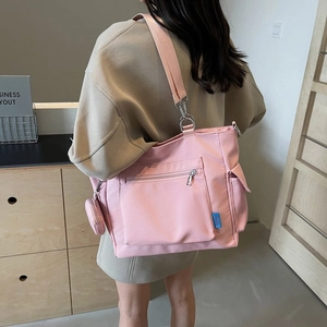 Borsa tote in nylon rosa con tracolla larga e mini portamonete indossata da modella