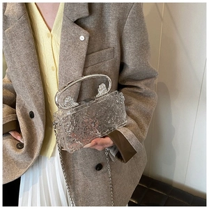 Detail of transparent acrylic box bag with ice-crack texture and silver metal handle