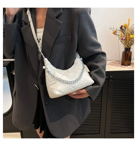 Close-up of white quilted crossbody bag featuring silver chain strap and refined stitching