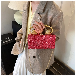 Detail of red pleated evening bag with gold lion head handle and metal chain strap