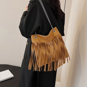 Brown suede crossbody bag with fringe details and silver chain strap shown on model