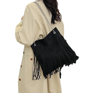 Retro black fringe crossbody bag with silver chain strap on model in beige coat