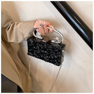 Detail of black acrylic box bag with stone texture and lion head metal ring handle