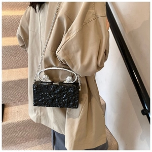 Detail of black glossy rock texture acrylic box bag with eagle-head metal ring handle