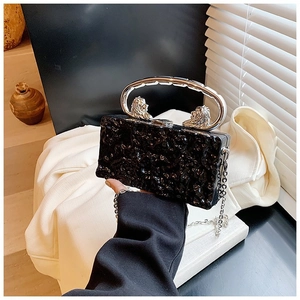 Detail of black acrylic box bag with silver lion head handle and lava texture surface