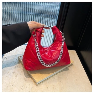 Red quilted leather handbag with silver chain strap on elegant marble surface