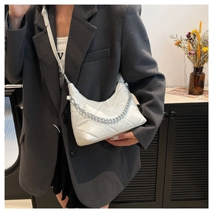 White quilted crossbody bag with silver chain strap shown on model shoulder