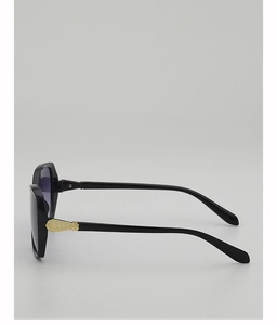 Detail of oversized black sunglasses with golden hollow carved metal temples and purple lenses