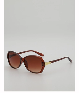 Detail of oversized sunglasses showing brown translucent frame and gold embossed metal hinge