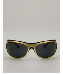 Detail of matte gold curved frame and dark lenses on futuristic Y2K style sunglasses