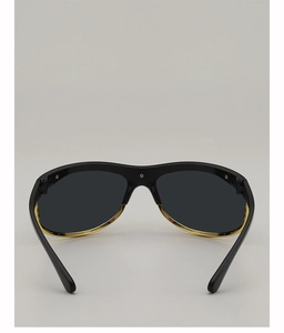 Detail view of large frame sunglasses featuring golden metal trim and silver hinge hardware