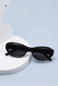 Detail of black oval cat-eye sunglasses on a white pedestal with professional studio lighting