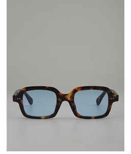 Detail of tortoise frame sunglasses with blue tinted lenses and metal rivet accents