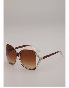 Detail of oversized sunglasses featuring floral metal hinges and brown gradient lenses