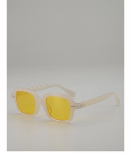 Detail of vintage square beige sunglasses featuring vibrant yellow lenses and metal studs