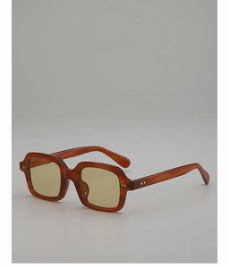 Detail of amber tortoiseshell sunglasses with yellow lenses and rivet accents
