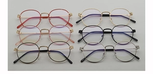 Flat lay of vintage round metal eyeglass frames in red gold pink black and silver