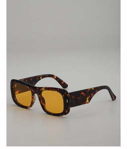 Close-up of square tortoiseshell sunglasses featuring orange lenses and metal rivets